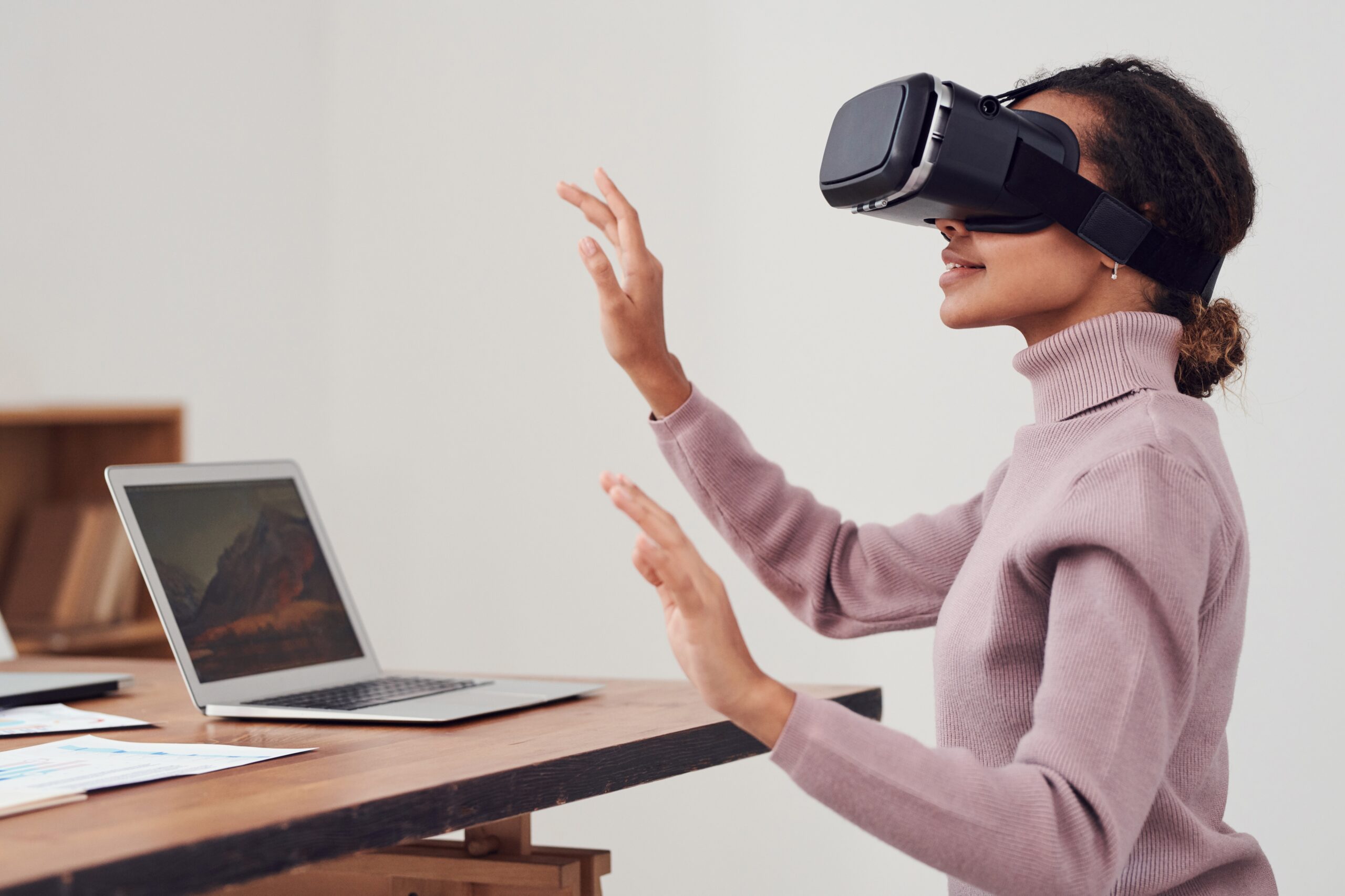 Frau hat eine VR-Brille an und sitzt vor ihrem Laptop.